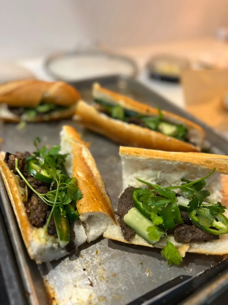 Bánh mì on a baking tray, split and filled with herbs and greens