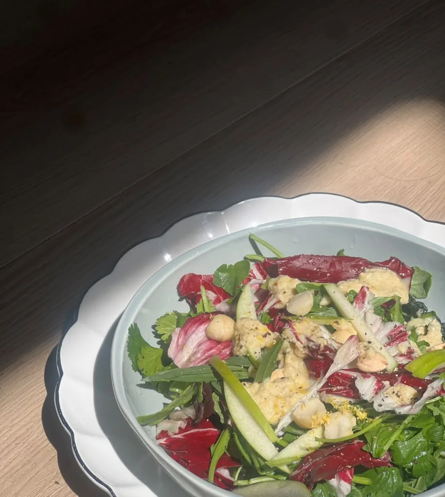 A salad of radicchio, leaves and shaved cheese on a fluted plate