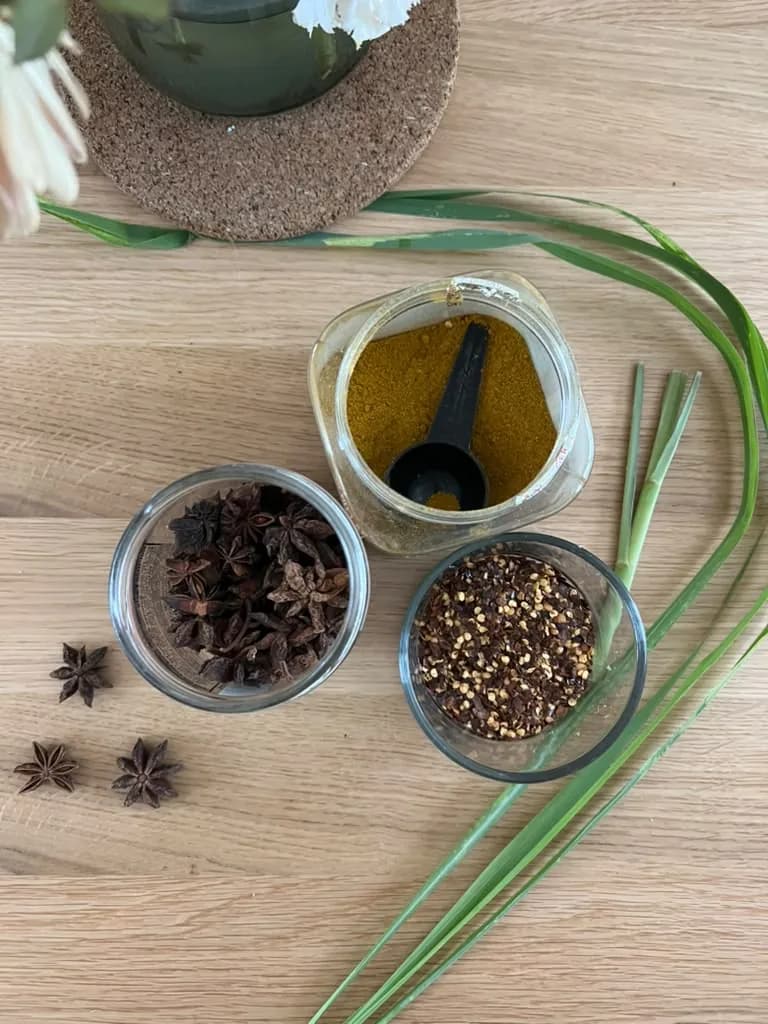 Star anise, cloves, peppercorns and turmeric in small glass bowls